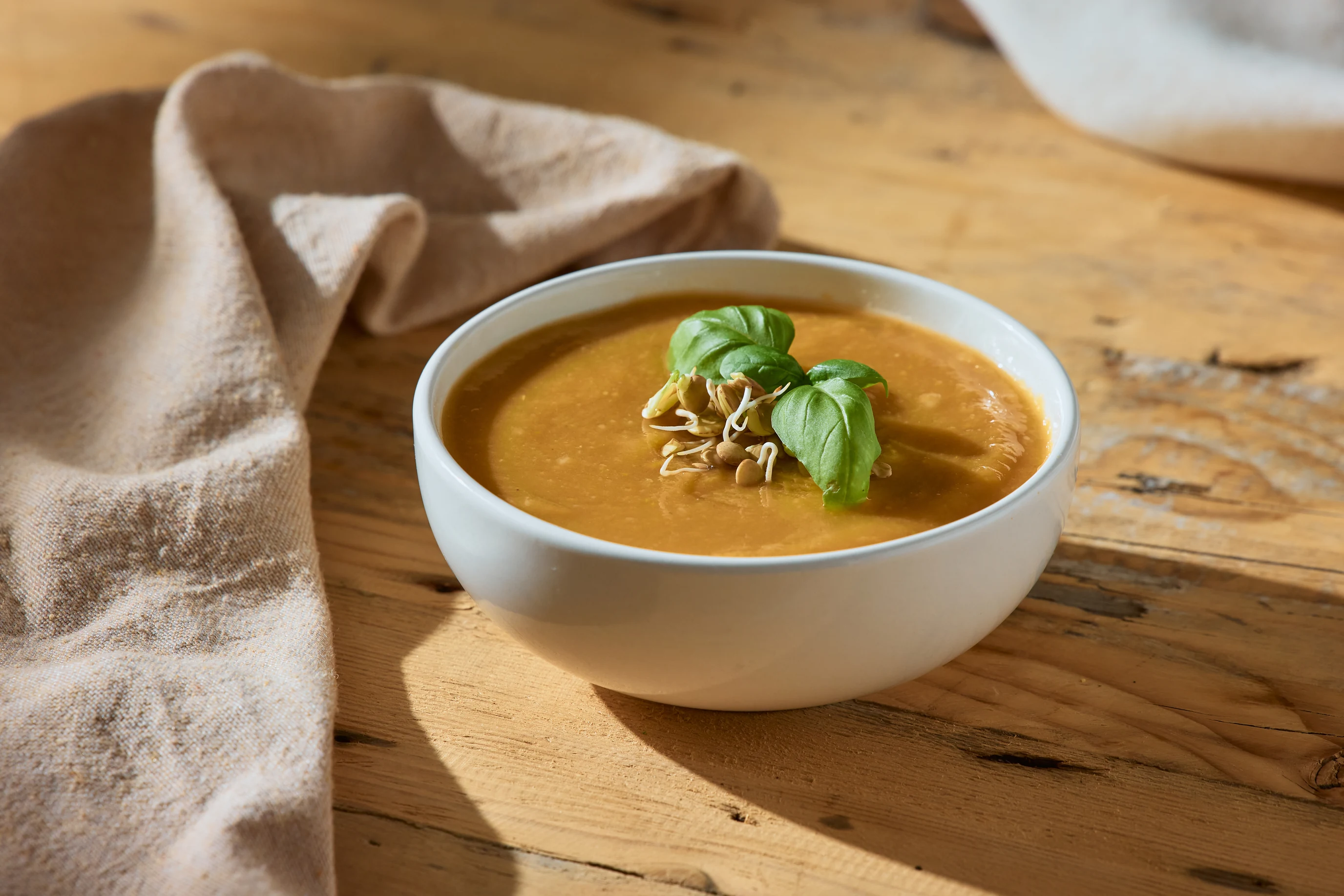 Bowl of nourishing soup topped with sprouts and basil